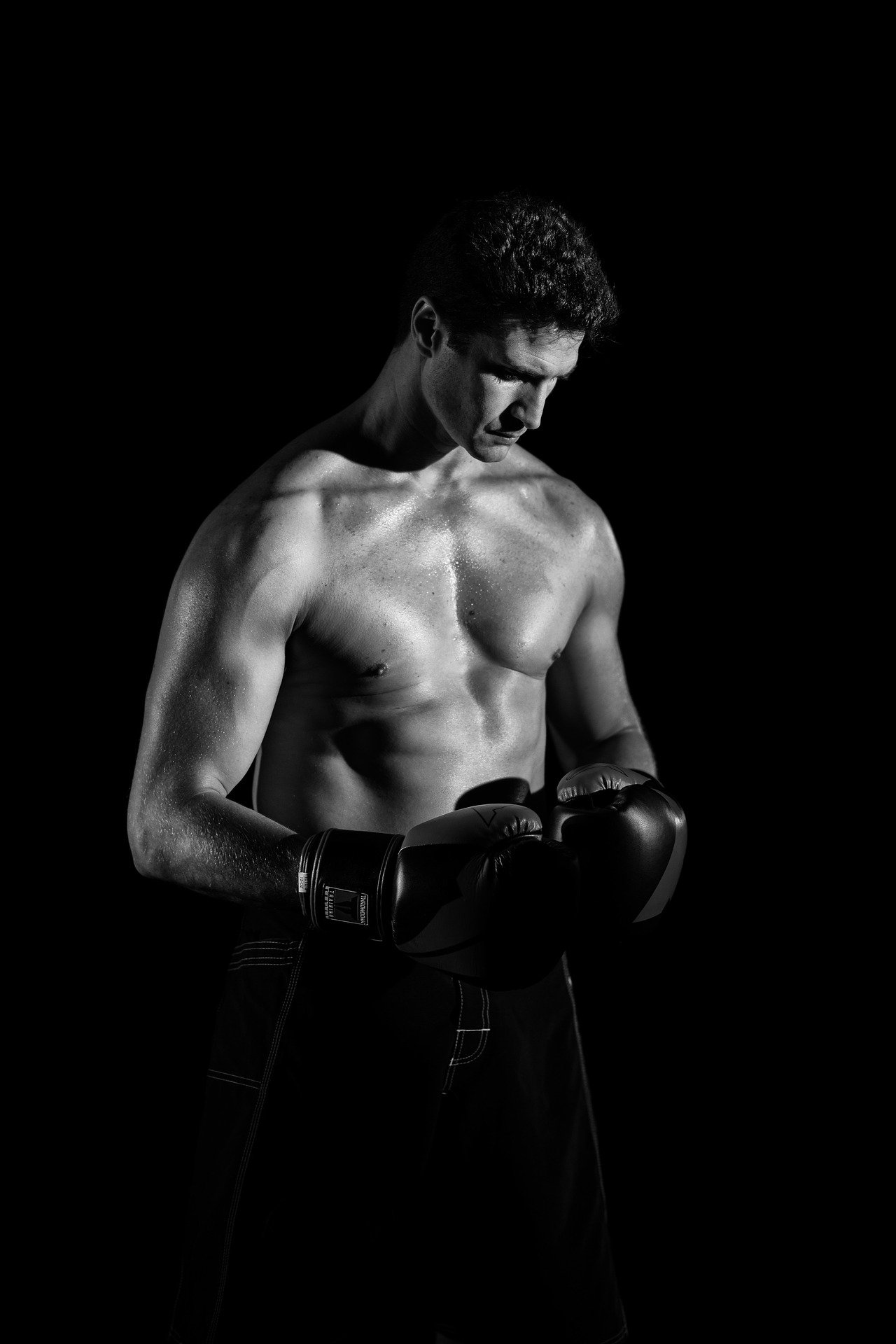 黑色背景前，一名戴着手套，身形健壮的拳击手手机壁纸图片