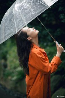 李沁穿橘色外套手持雨伞现身雨天户外慵懒随性写真图片